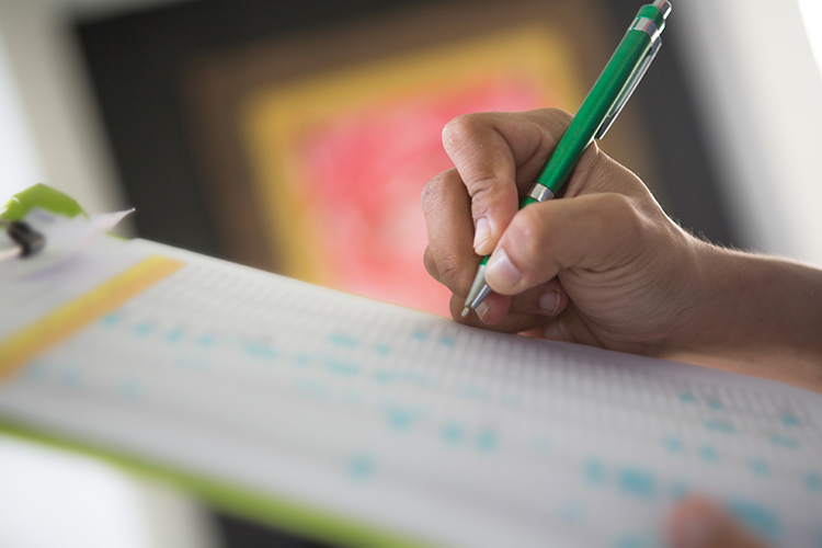 Human hand holding pen and checklist, selective focus