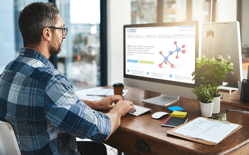 Man working at desk looking at QMS website