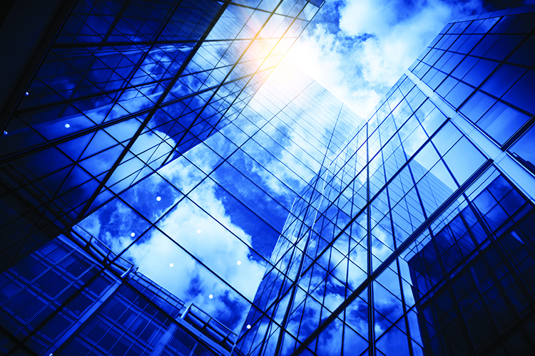 view of a contemporary glass skyscraper reflecting the blue sky