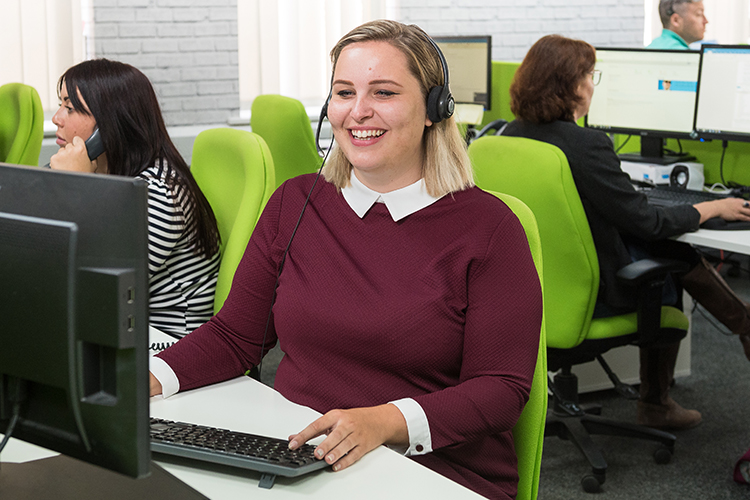 Lady smiling and sitting at a desk in call centre