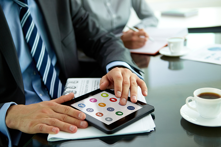 Man working at office desk with tablet and coffee