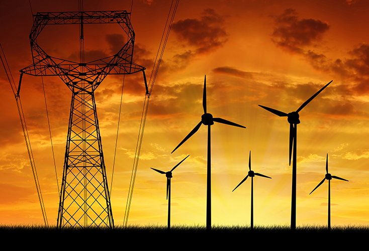 Electric pylon and windfarm silhouetted against orange sunset