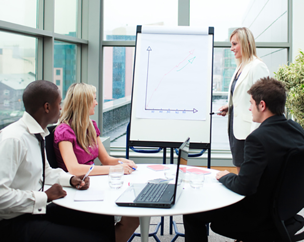 Lady with flip board presenting to people sat at a desk