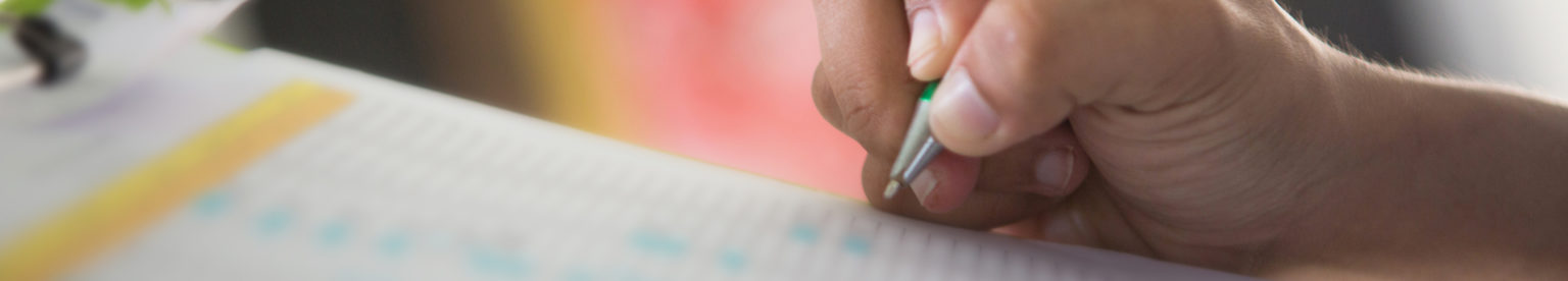 Human hand holding pen and checklist, selective focus