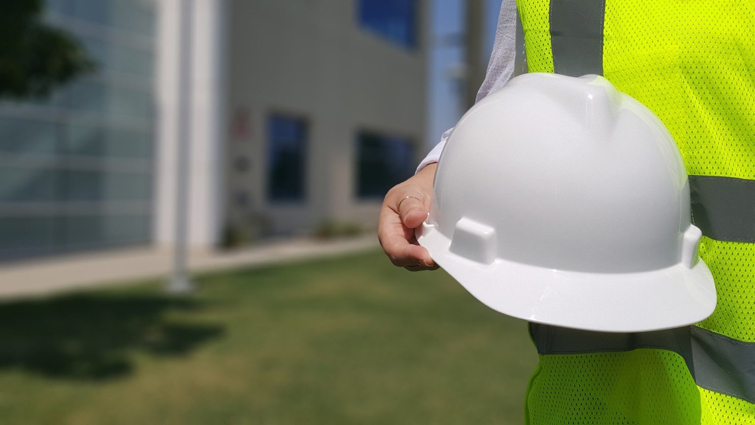 Person in high visibility jacket holding a hard hat