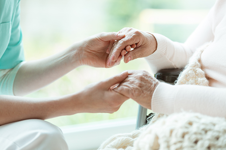 Carer holding an elderly person's hands