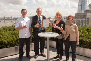 Two men and two women holding champagne glasses on roof top garden