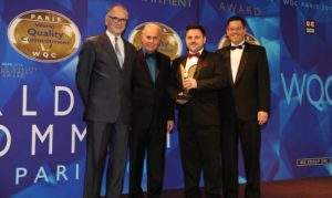 Men in suits standing a trophy at an award ceremony