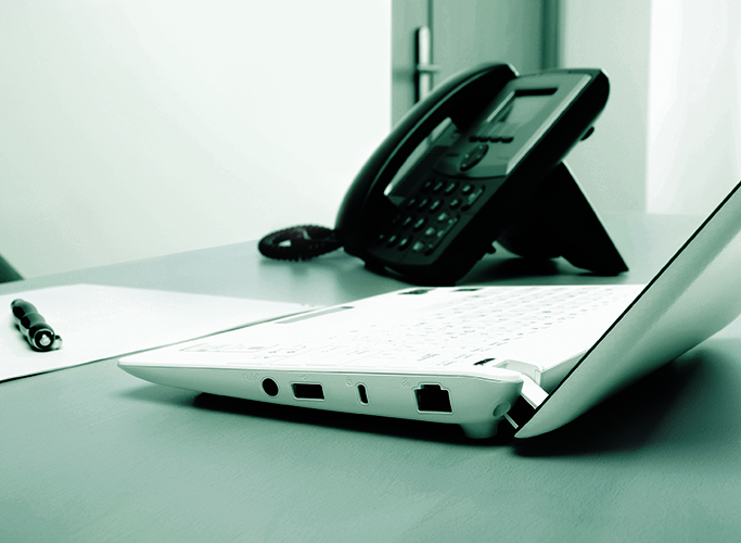 Telephone, pen, paper and laptop on a desk