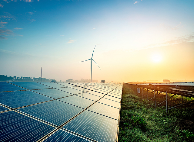 Wind and solar farm in front of sunset