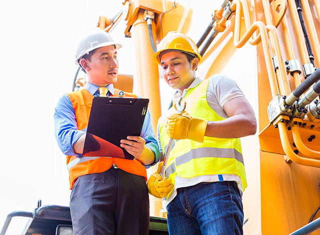 Two men wearing protective work wear in front of machinery