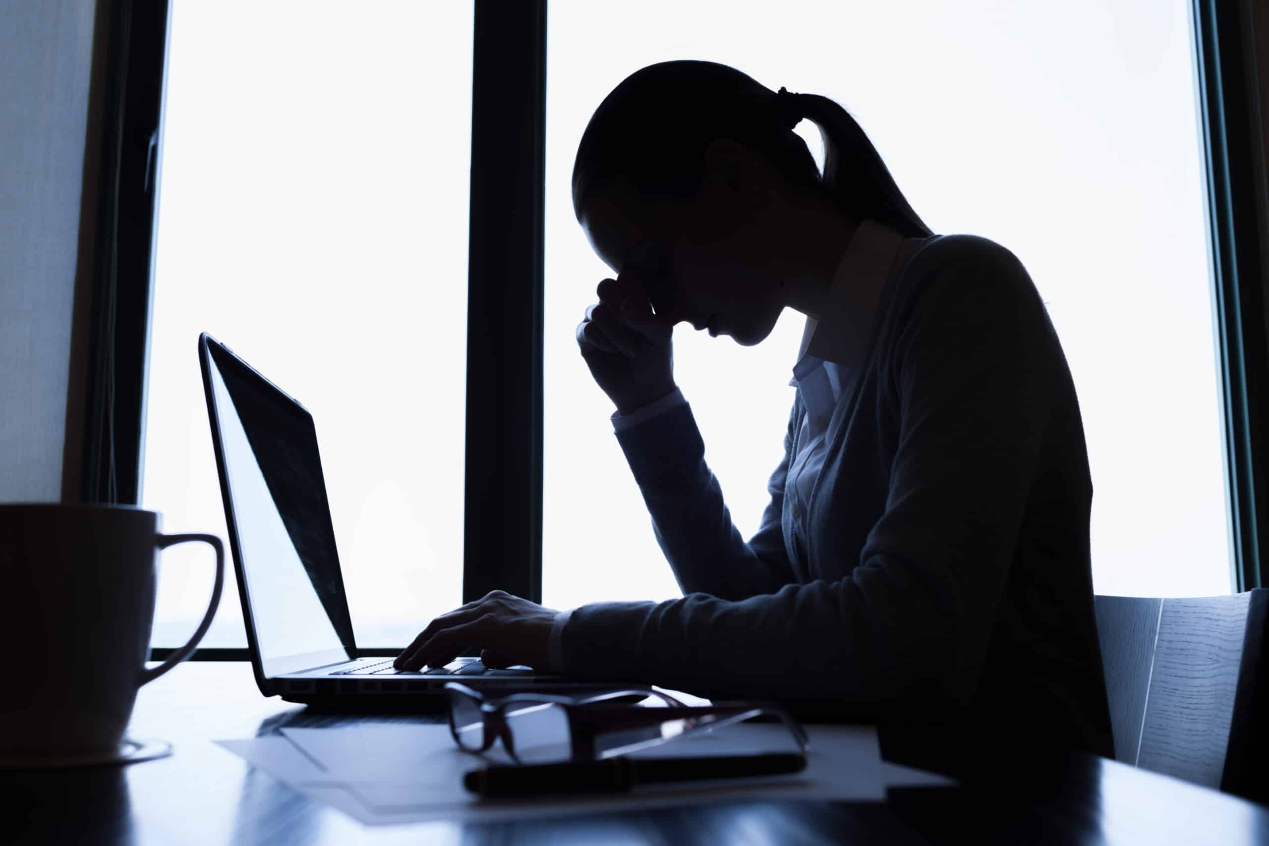 Photo of a person sat at desk with head in hand