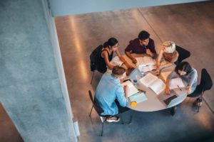 Workplace colleagues gathering around a desk discussing a task